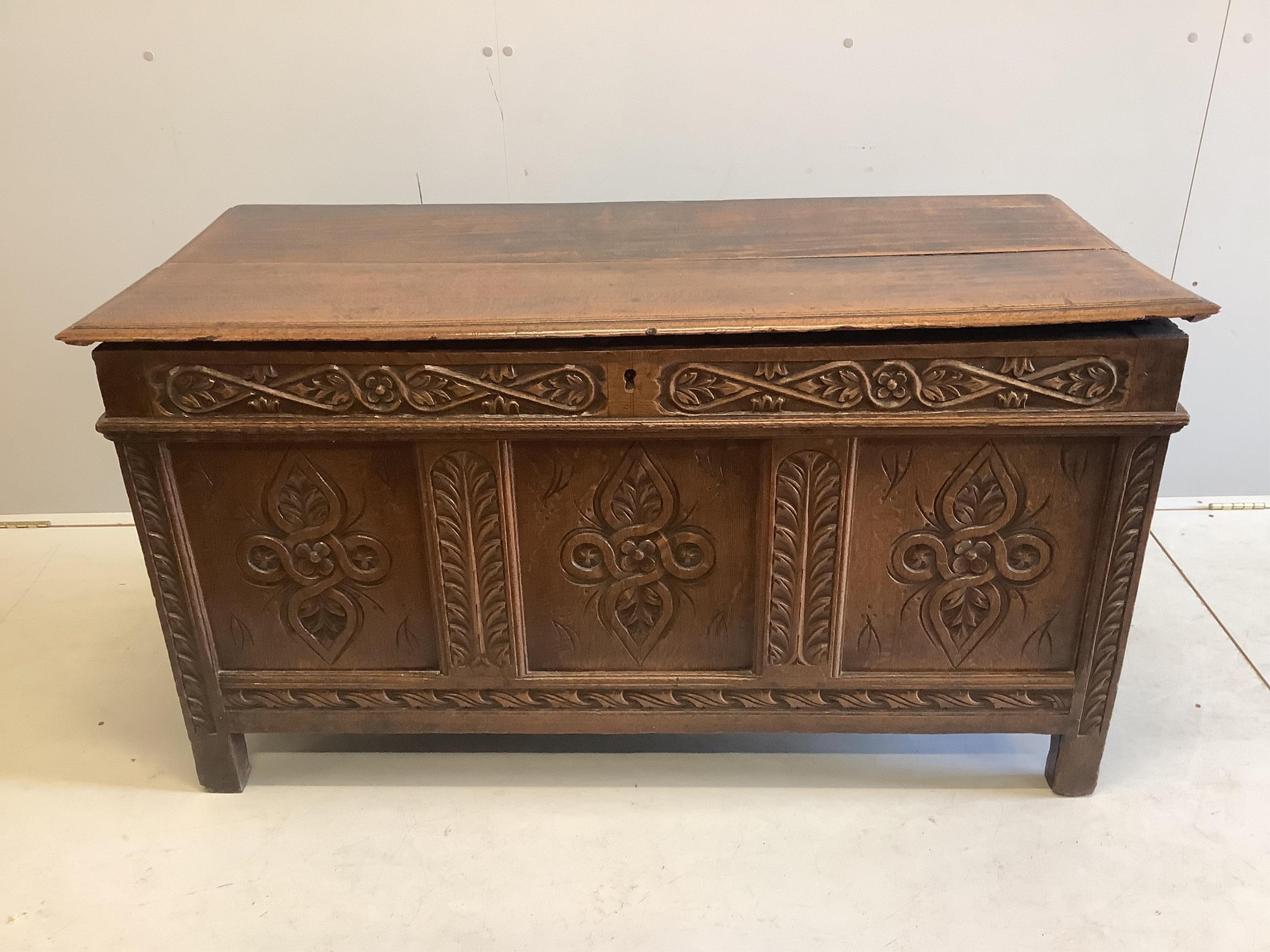 An early 18th century carved oak coffer with two plank top, width 133cm, depth 59cm, height 70cm